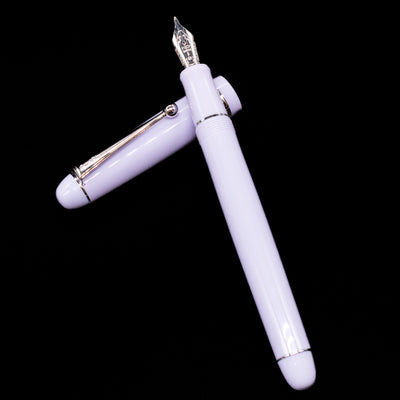 Pilot Custom 74 Fountain Pen - Lavender Fog laying on top of its cap in a crossed position showing full view of the entire uncapped pen.