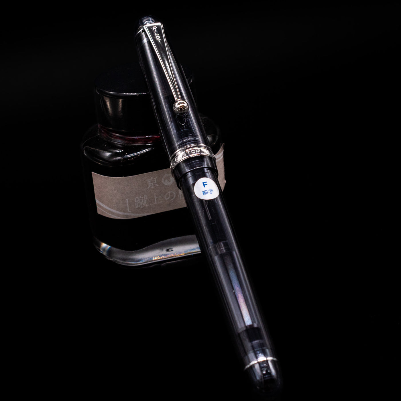 Pilot Custom 74 Fountain Pen - Smoke capped, leaning against an ink bottle. 