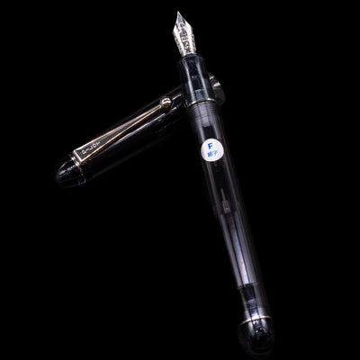 Pilot Custom 74 Fountain Pen - Smoke  laying on top of its cap in a crossed position showing full view of the entire uncapped pen.