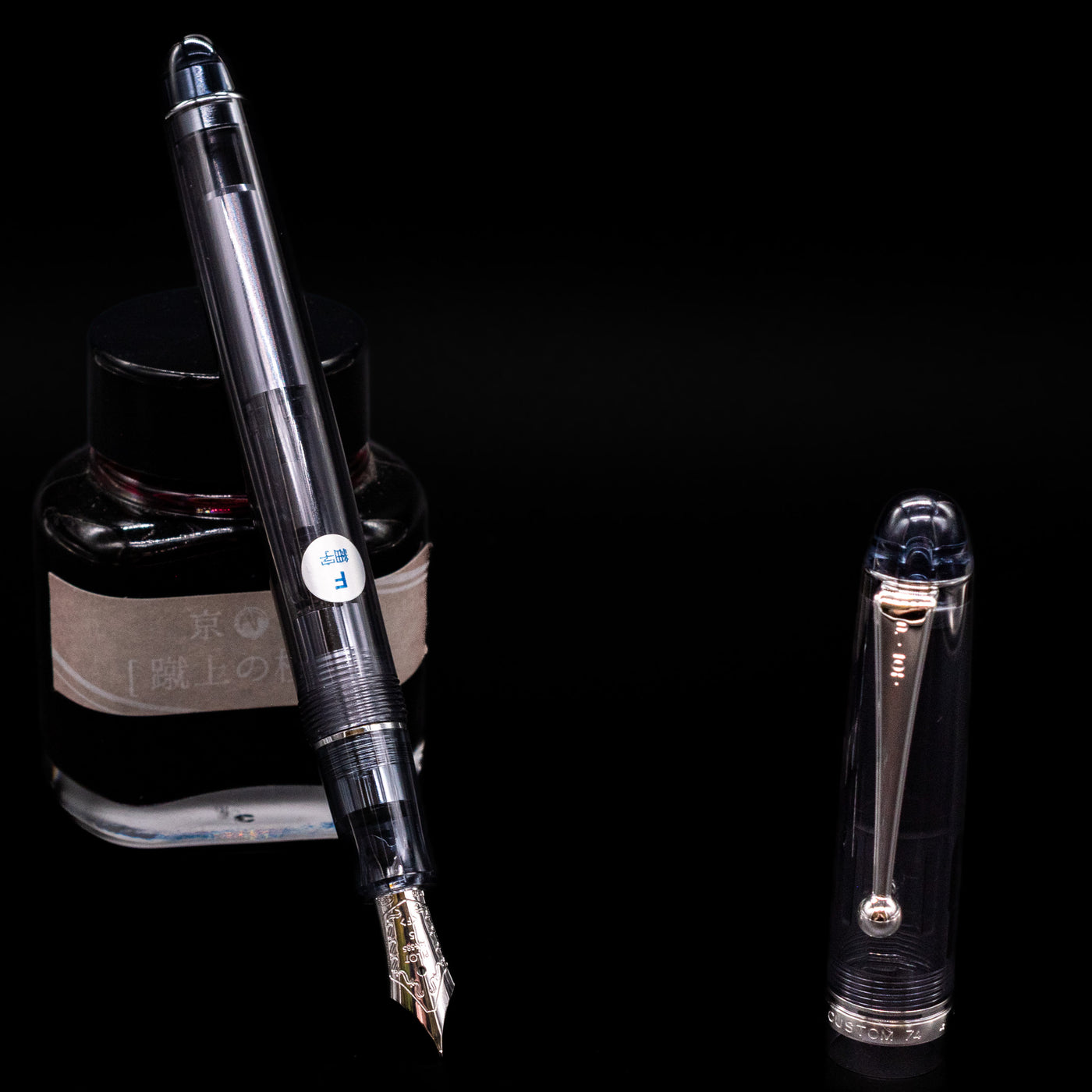 Pilot Custom 74 Fountain Pen - Smoke leaning on an ink bottle uncapped showcasing the detailing on the nib.