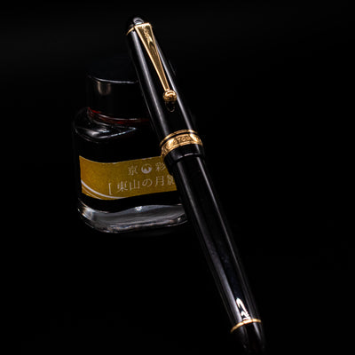 Pilot Custom 742 Black Fountain Pen - Preowned capped, leaning against an ink bottle. 