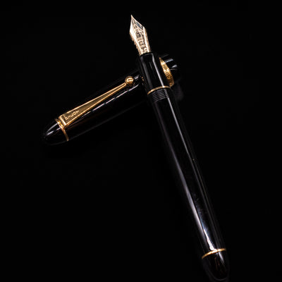 Pilot Custom 742 Black Fountain Pen - Preowned laying on top of its cap in a crossed position showing full view of the entire uncapped pen.