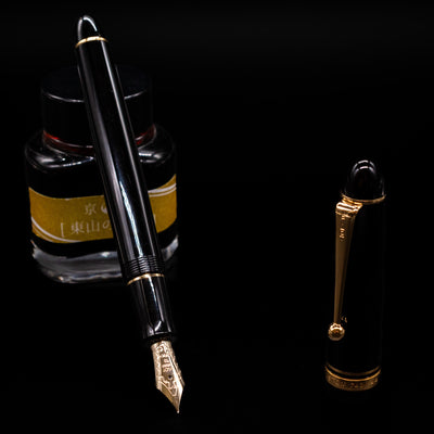 Pilot Custom 742 Black Fountain Pen - Preowned leaning on an ink bottle uncapped showcasing the detailing on the nib.