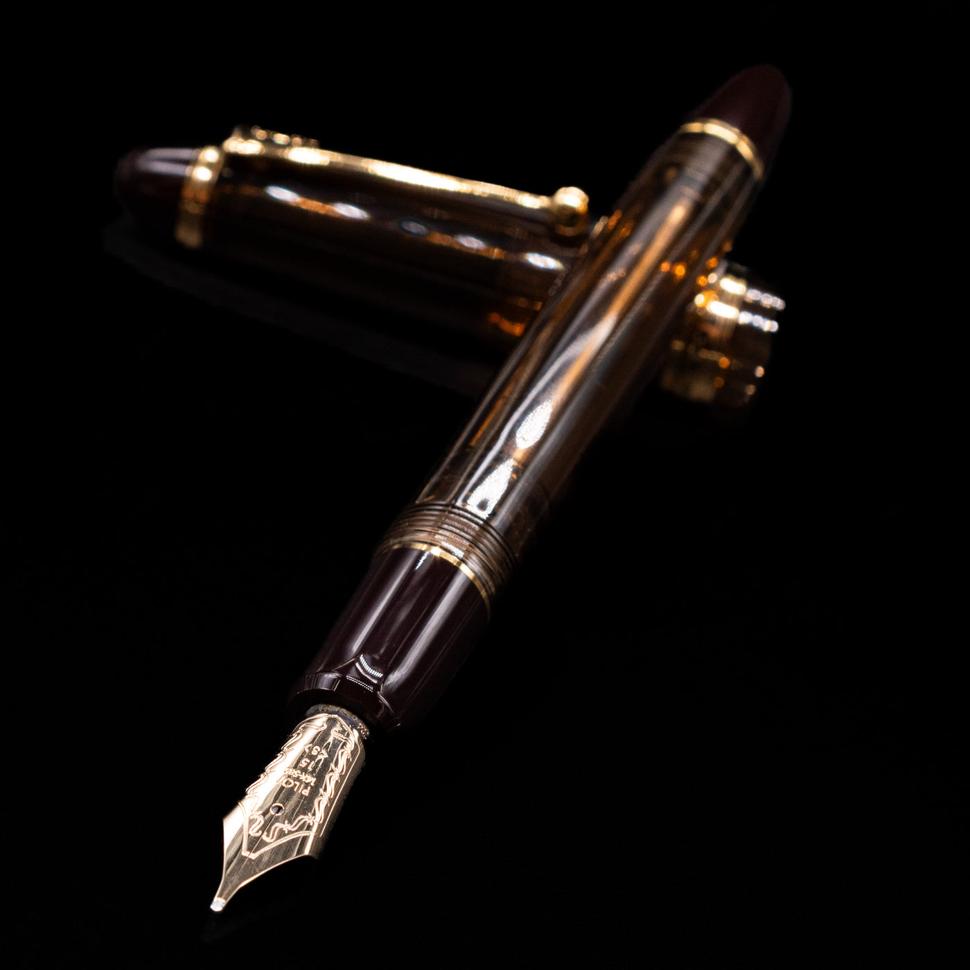 Pilot Custom 823 Amber Fountain Pen laying across its own cap, crossed, with a focus on the nib.