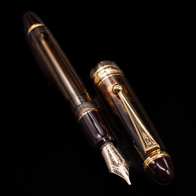 A full view of the Pilot Custom 823 Amber Fountain Pen uncapped, with its cap laying next to the pen. 