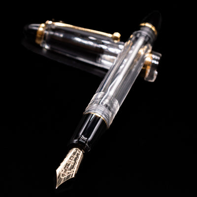 Pilot Custom 823 Fountain Pen - Clear laying across its own cap, crossed, with a focus on the nib.