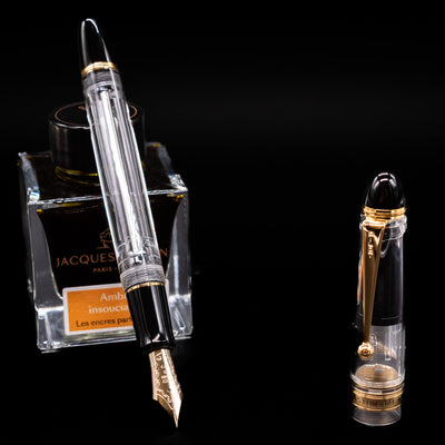 Pilot Custom 823 Fountain Pen - Clear leaning on an ink bottle uncapped showcasing the detailing on the nib.