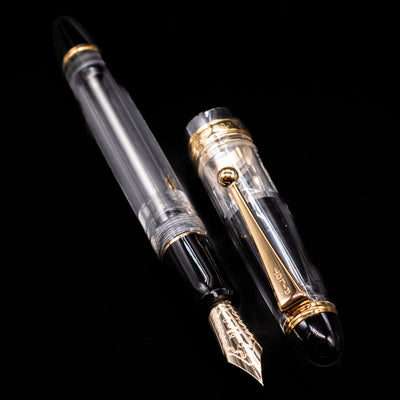 A full view of the Pilot Custom 823 Fountain Pen - Clear uncapped, with its cap laying next to the pen. 