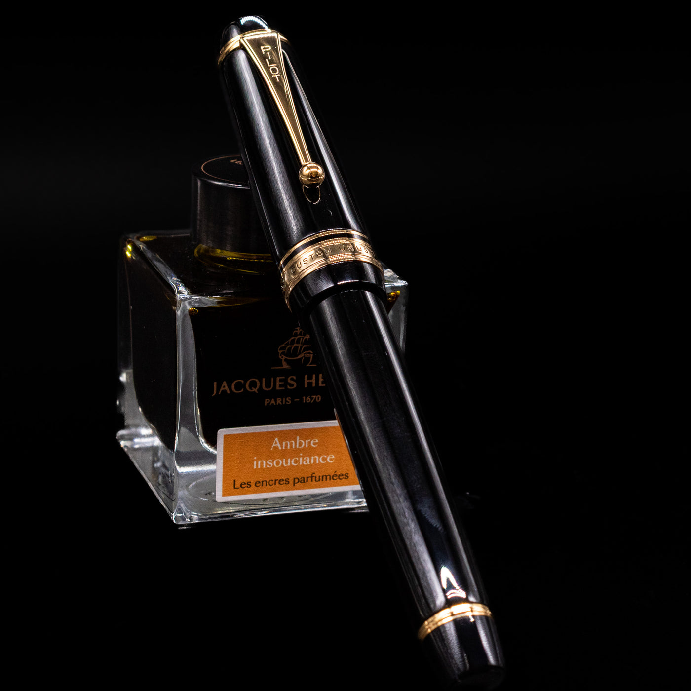 Pilot Custom Urushi Fountain Pen - Black capped, leaning against an ink bottle. 