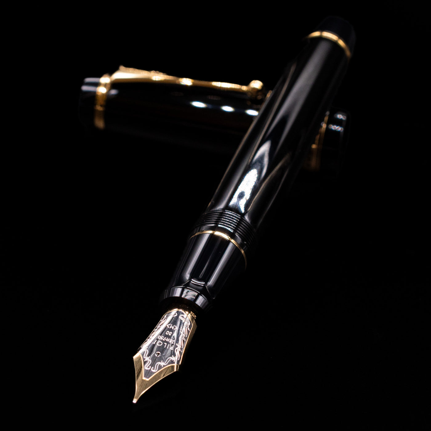 Pilot Custom Urushi Fountain Pen - Black laying across its own cap, crossed, with a focus on the nib.