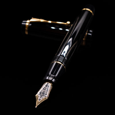 Pilot Custom Urushi Fountain Pen - Black laying across its own cap, crossed, with a focus on the nib.
