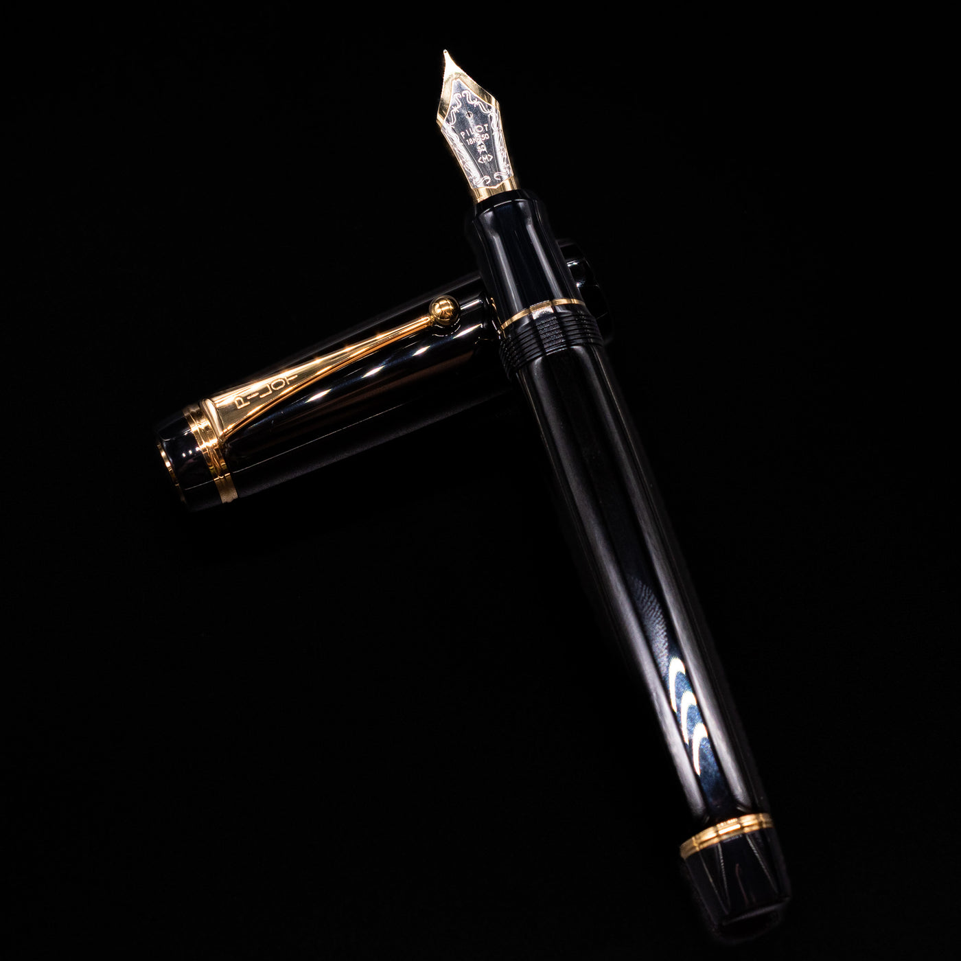 Pilot Custom Urushi Fountain Pen - Black laying on top of its cap in a crossed position showing full view of the entire uncapped pen.