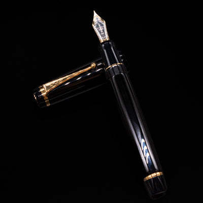 Pilot Custom Urushi Fountain Pen - Black laying on top of its cap in a crossed position showing full view of the entire uncapped pen.