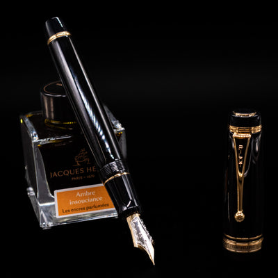 Pilot Custom Urushi Fountain Pen - Black leaning on an ink bottle uncapped showcasing the detailing on the nib.