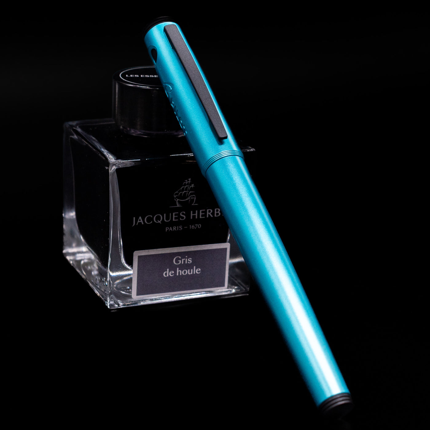 Pilot Explorer Turquoise Blue Metal Fountain Pen capped, leaning against an ink bottle. 