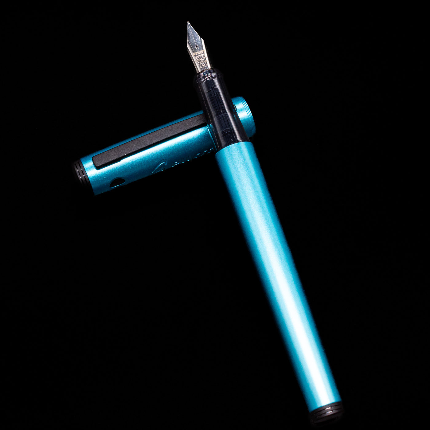 Pilot Explorer Turquoise Blue Metal Fountain Pen laying on top of its cap in a crossed position showing full view of the entire uncapped pen.