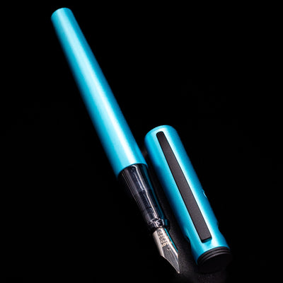 A full view of the Pilot Explorer Turquoise Blue Metal Fountain Pen uncapped, with its cap laying next to the pen. 