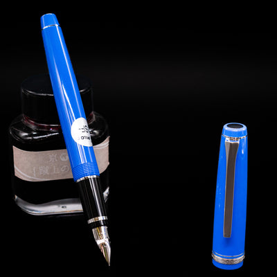 Pilot Falcon Fountain Pen - Blue leaning on an ink bottle uncapped showcasing the detailing on the nib.