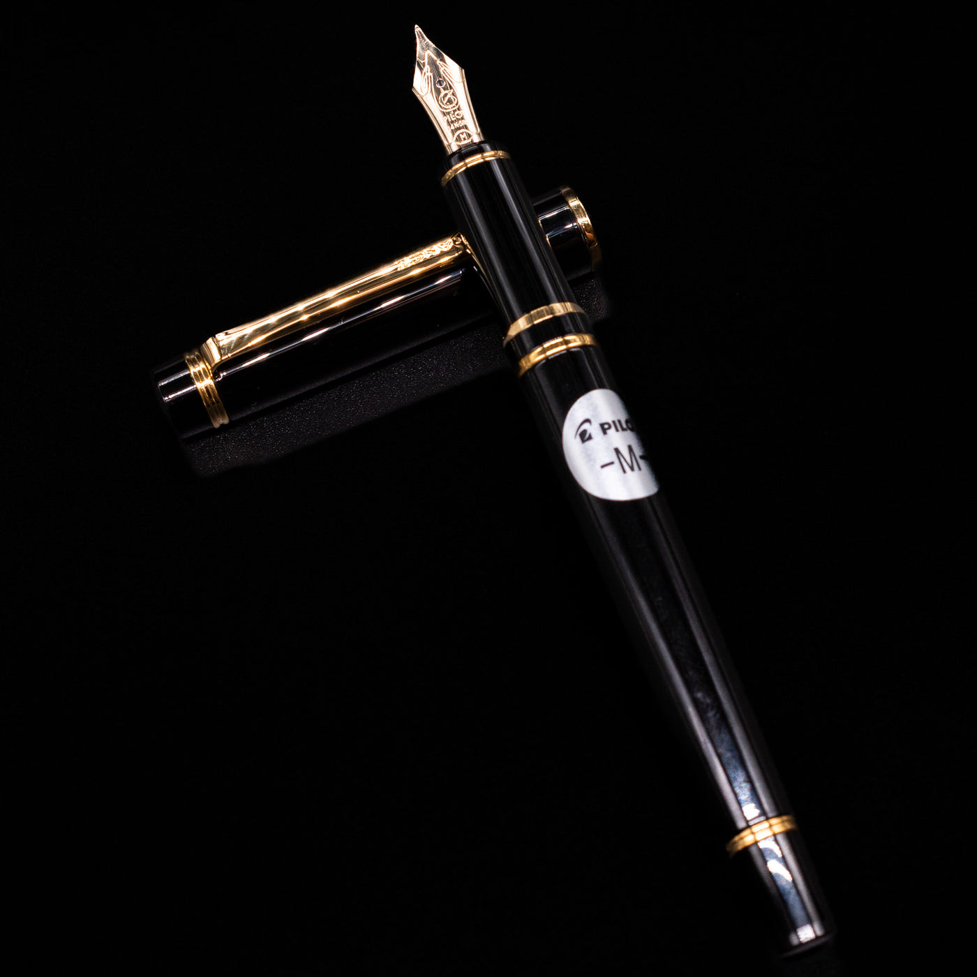 Pilot Grance Fountain Pen - Black laying on top of its cap in a crossed position showing full view of the entire uncapped pen.