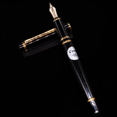 Pilot Grance Fountain Pen - Black laying on top of its cap in a crossed position showing full view of the entire uncapped pen.