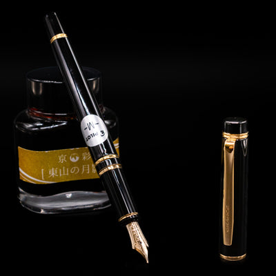 Pilot Grance Fountain Pen - Black leaning on an ink bottle uncapped showcasing the detailing on the nib.