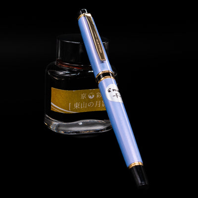  Pilot Grance Fountain Pen - Light Blue capped, leaning against an ink bottle. 