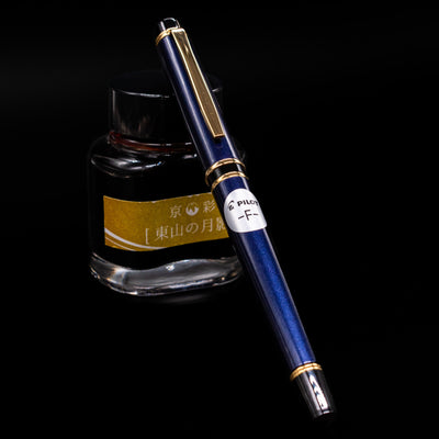 Pilot Grance Fountain Pen - Navy Blue capped, leaning against an ink bottle. 