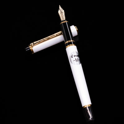 Pilot Grance Fountain Pen - Pearl White laying on top of its cap in a crossed position showing full view of the entire uncapped pen.