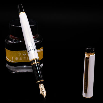 Pilot Grance Fountain Pen - Pearl White leaning on an ink bottle uncapped showcasing the detailing on the nib.