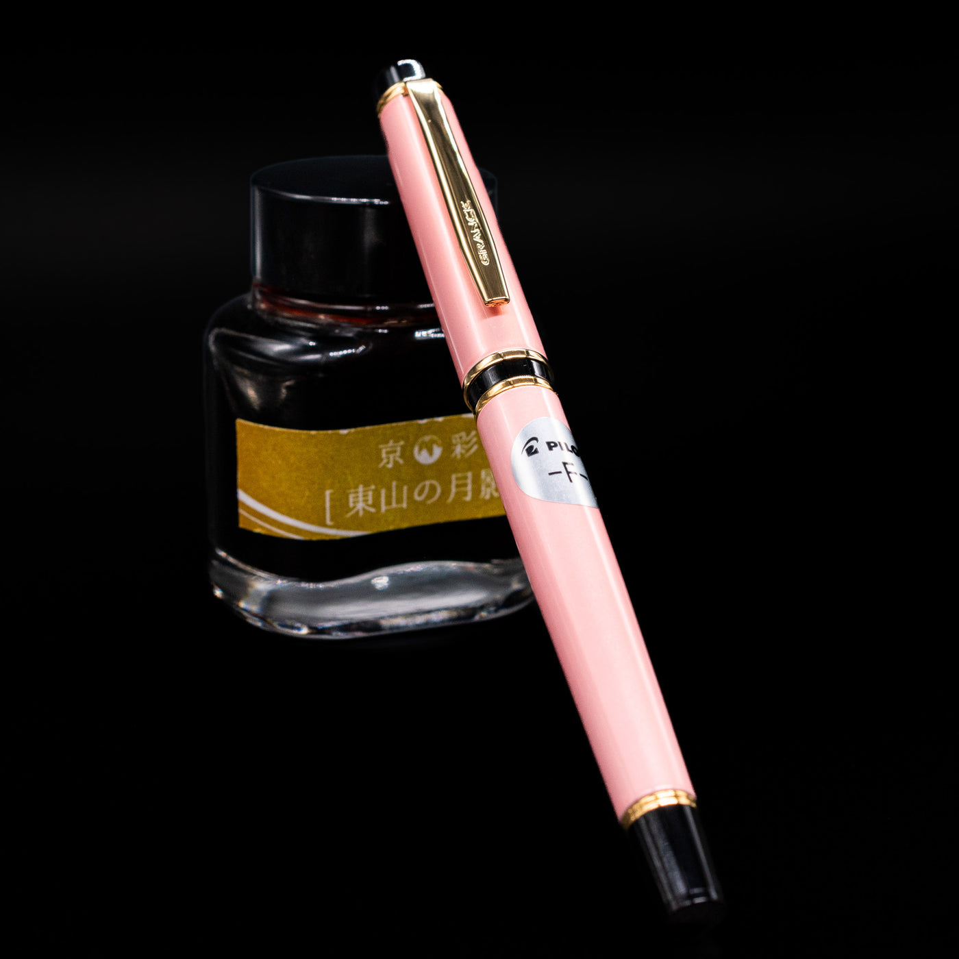 Pilot Grance Fountain Pen - Pink capped, leaning against an ink bottle. 