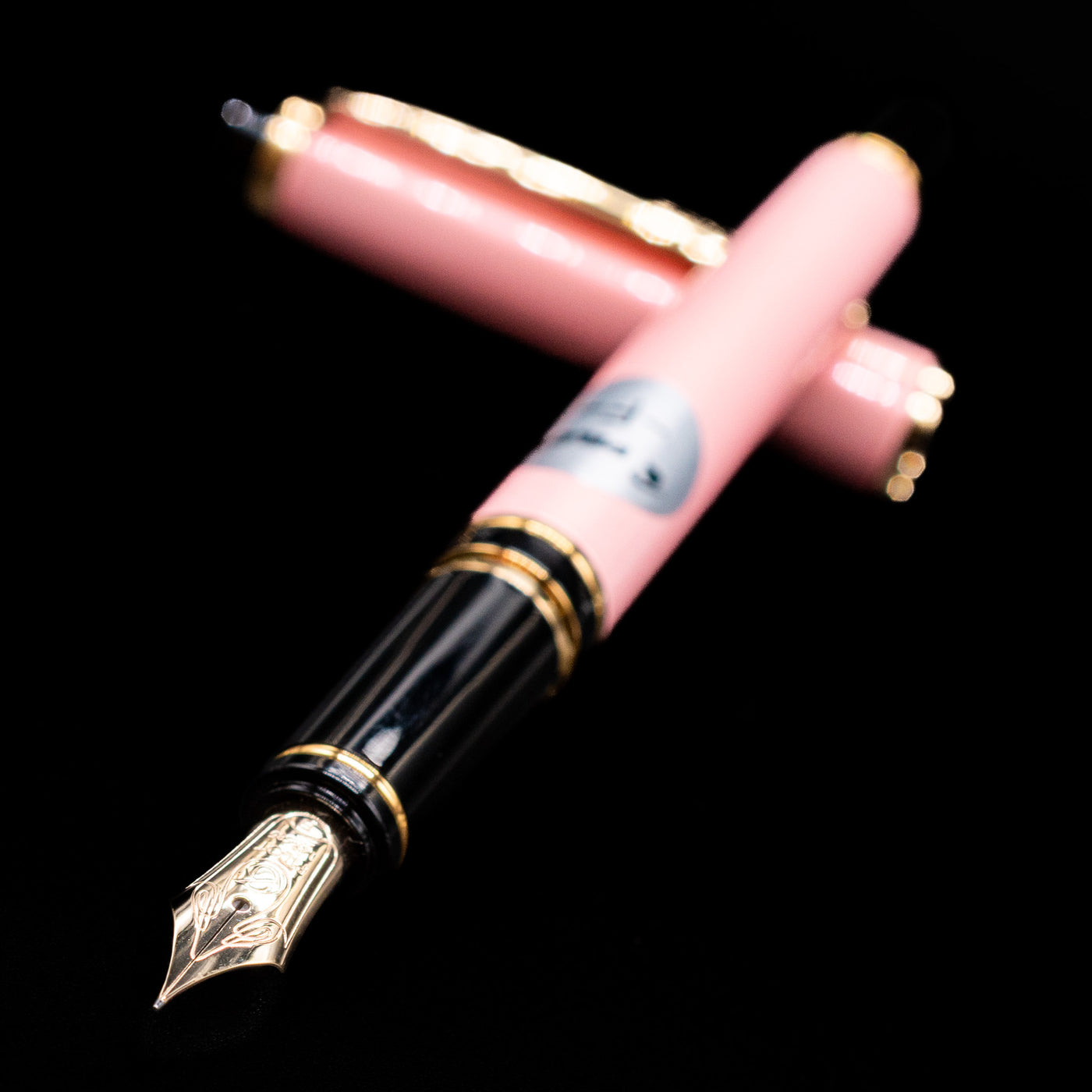  Pilot Grance Fountain Pen - Pink laying across its own cap, crossed, with a focus on the nib.