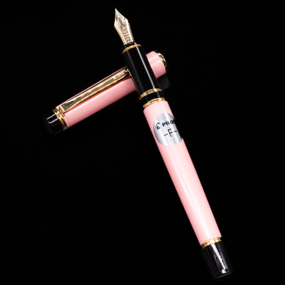 Pilot Grance Fountain Pen - Pink laying on top of its cap in a crossed position showing full view of the entire uncapped pen.