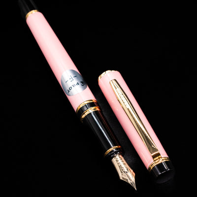 A full view of the Pilot Grance Fountain Pen - Pink uncapped, with its cap laying next to the pen. 