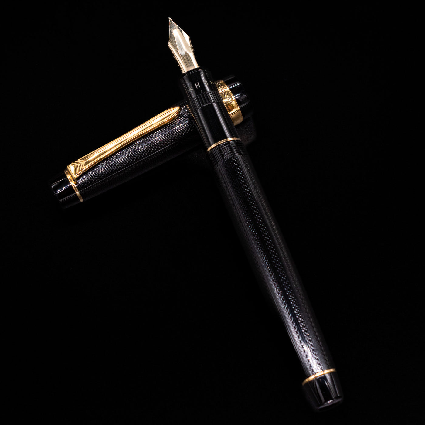 Preowned Pilot Justus 95 Net Black fountain pen and its cap arranged in a crossed layout, showcasing the barrel’s detailed net-pattern texture and the warm tone of its gold trim.