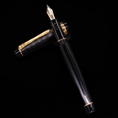 Preowned Pilot Justus 95 Net Black fountain pen and its cap arranged in a crossed layout, showcasing the barrel’s detailed net-pattern texture and the warm tone of its gold trim.