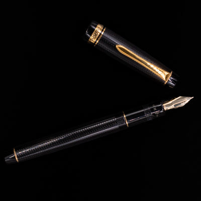 Overhead view of the Preowned Pilot Justus 95 Net Black fountain pen, highlighting the symmetry of its design, glossy black net-pattern finish, and gleaming gold clip.