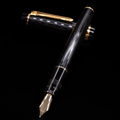 Preowned Pilot Justus 95 Net Black fountain pen and cap arranged in a crossed position, with the shot focused closely on the engraved 14k gold nib and the pen’s elegant gold trim.