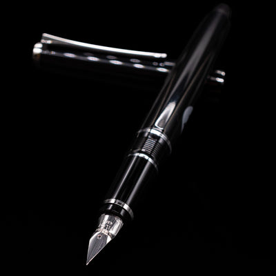 Pilot Metal Falcon Fountain Pen - Black laying across its own cap, crossed, with a focus on the nib.