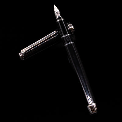 Pilot Metal Falcon Fountain Pen - Black laying on top of its cap in a crossed position showing full view of the entire uncapped pen.