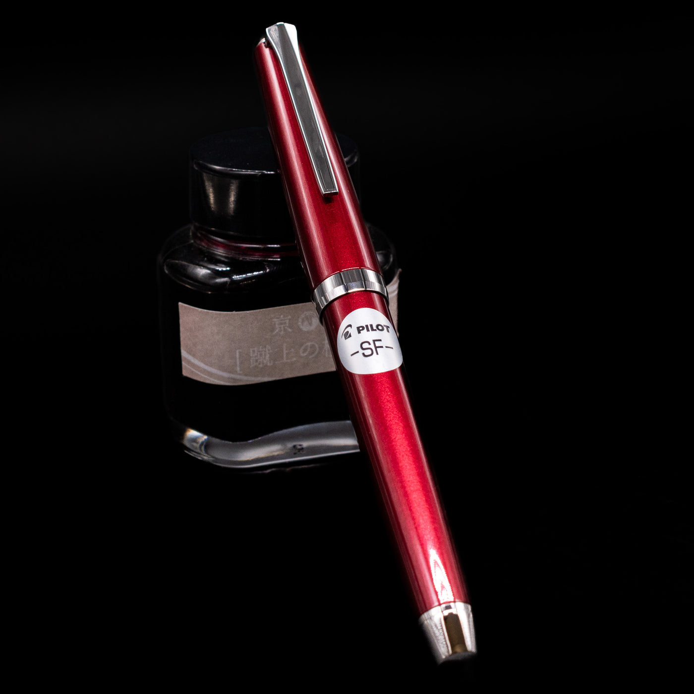 Pilot Metal Falcon Fountain Pen - Burgundy capped, leaning against an ink bottle. 