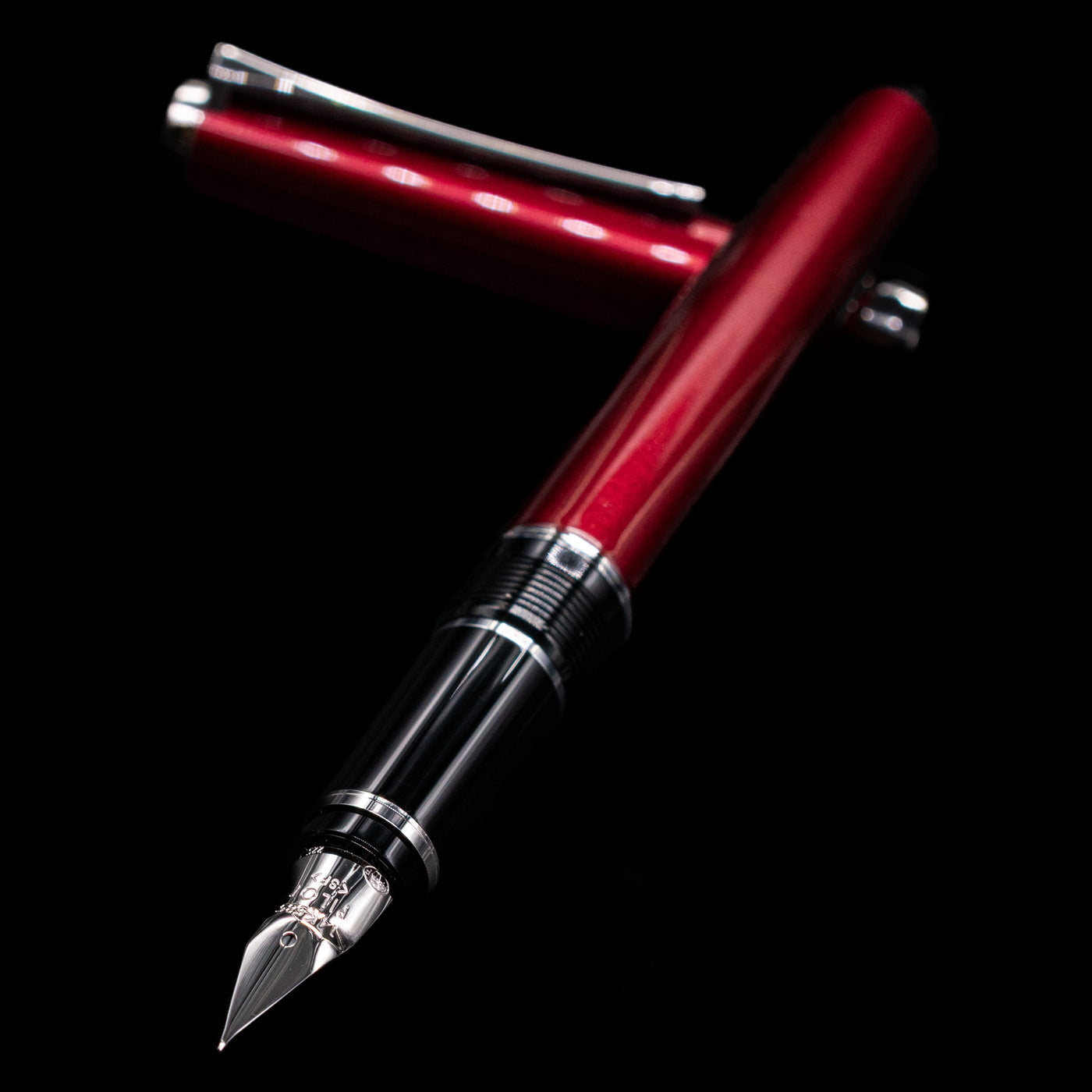 Pilot Metal Falcon Fountain Pen - Burgundy laying across its own cap, crossed, with a focus on the nib.