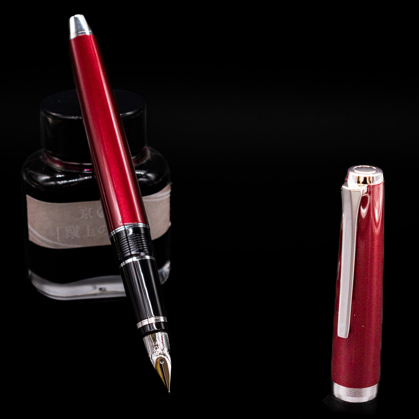 Pilot Metal Falcon Fountain Pen - Burgundy leaning on an ink bottle uncapped showcasing the detailing on the nib.