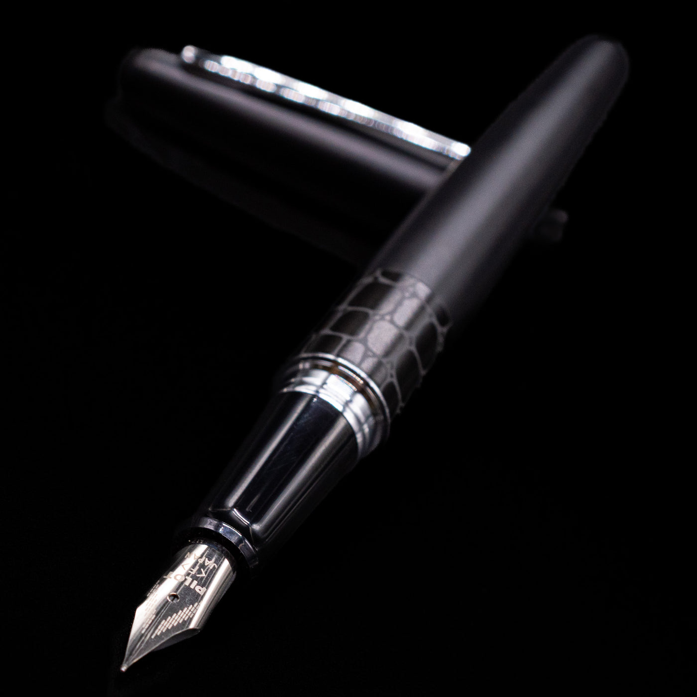 Pilot Metropolitan Fountain Pen - Crocodile laying across its own cap, crossed, with a focus on the nib.