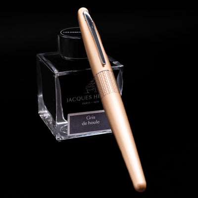 Pilot Metropolitan Fountain Pen - Gold Zig Zag capped, leaning against an ink bottle. 