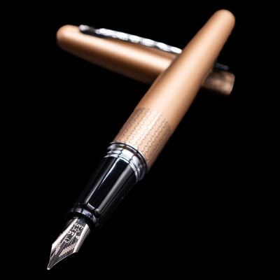 Pilot Metropolitan Fountain Pen - Gold Zig Zag laying across its own cap, crossed, with a focus on the nib.