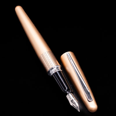 A full view of the Pilot Metropolitan Fountain Pen - Gold Zig Zag uncapped, with its cap laying next to the pen. 