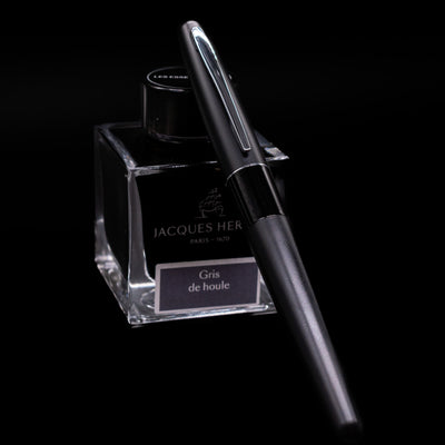 Pilot Metropolitan Fountain Pen - Plain Black capped, leaning against an ink bottle. 