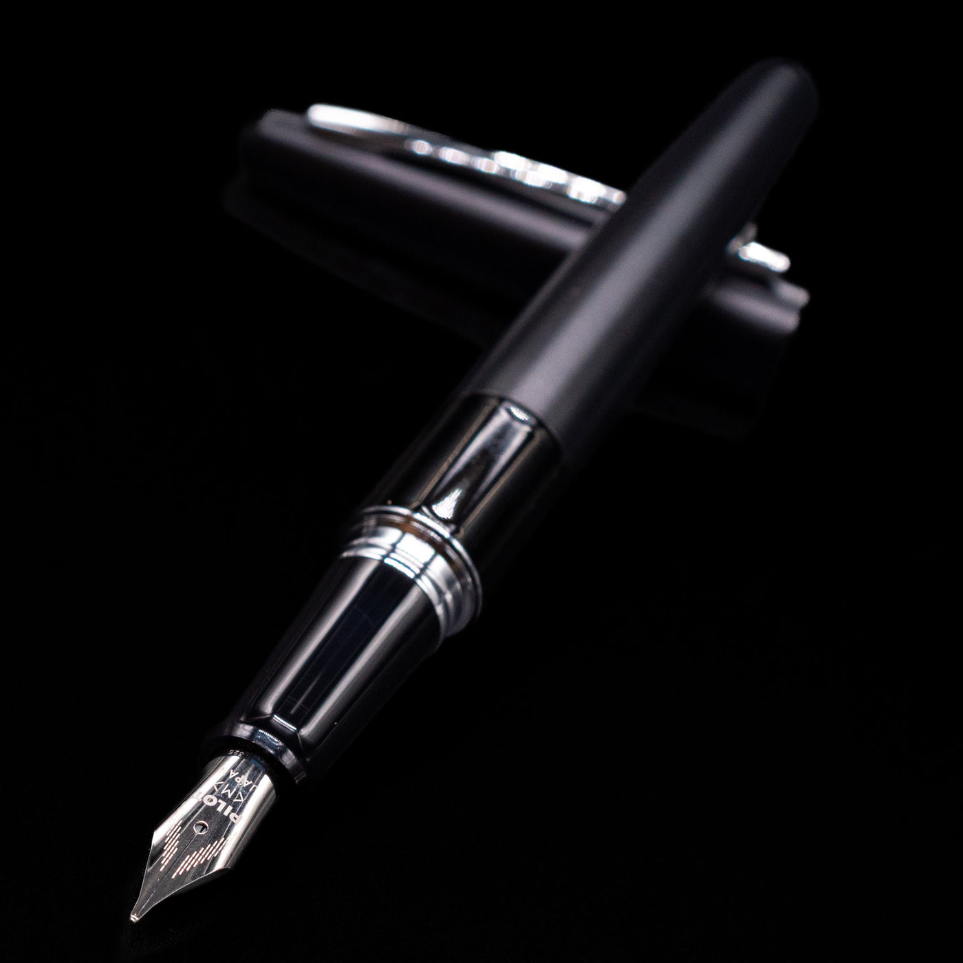 Pilot Metropolitan Fountain Pen - Plain Black laying across its own cap, crossed, with a focus on the nib.