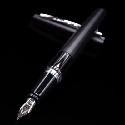 Pilot Metropolitan Fountain Pen - Plain Black laying across its own cap, crossed, with a focus on the nib.