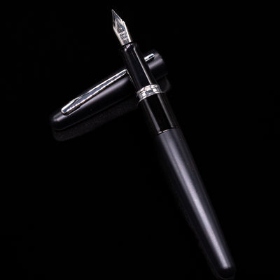 Pilot Metropolitan Fountain Pen - Plain Black laying on top of its cap in a crossed position showing full view of the entire uncapped pen.
